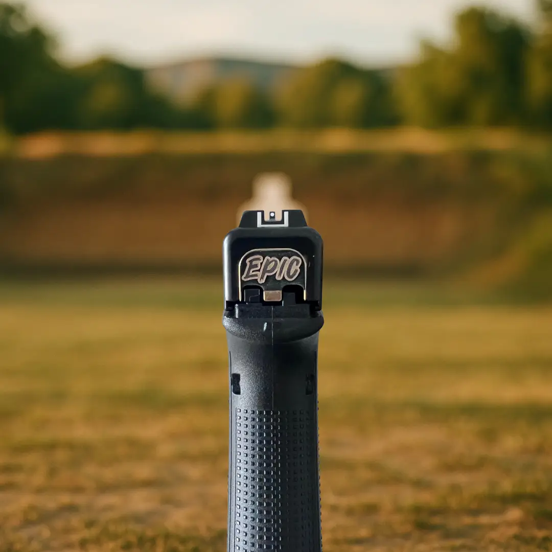 Epic engraved Glock backplate installed on handgun in outdoor range setting